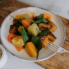 Waipawa Butchery Kitchen plate of roasted colourful vegetables in a white bowl, with a fork, sitting on a cutting board.