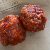 2 uncooked lamb rissoles sit on some brown paper with a Waipawa Butchery stamp.
