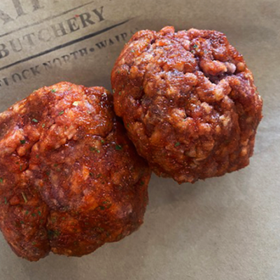 2 uncooked lamb rissoles sit on some brown paper with a Waipawa Butchery stamp.
